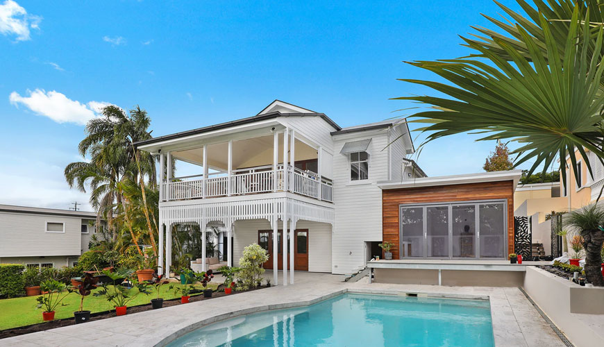 A white Two story home with an in-ground pool.